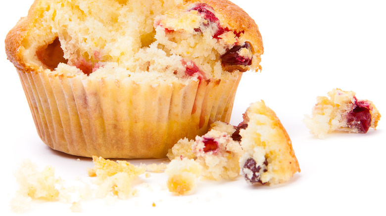 Crumbling cranberry muffin on white background