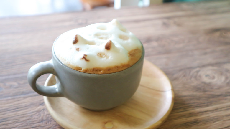 3-D coffee foam art in a cup on a wooden plate