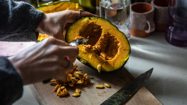 Person scooping seeds out of pumpkin