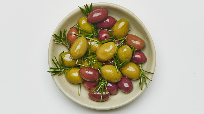 Overhead of a bowl of green and kalamata olives with rosemary