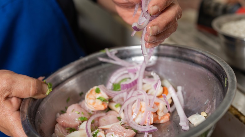 chef mixing ceviche by hand