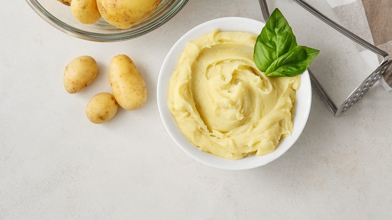 mashed potatoes with basil in bowl on table