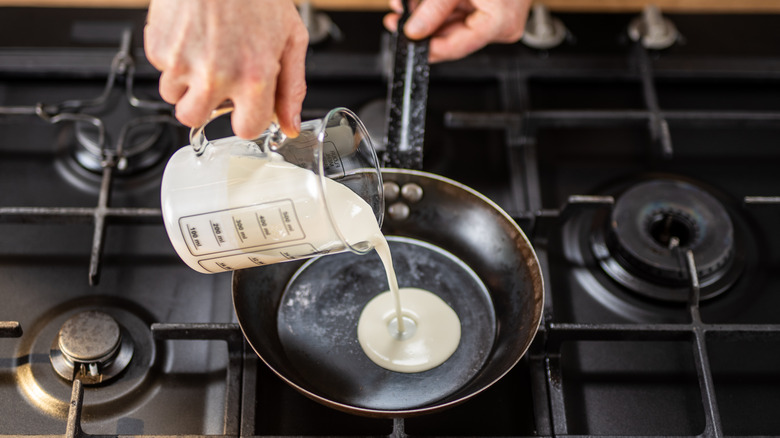 person pouring cream into a pan