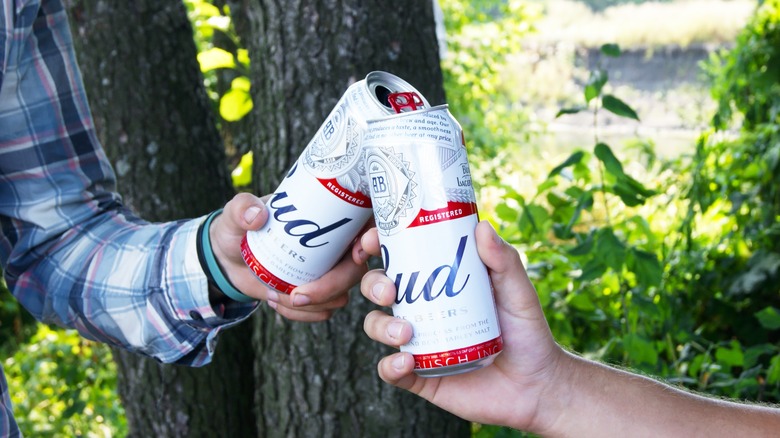 two people touching Budweiser cans 