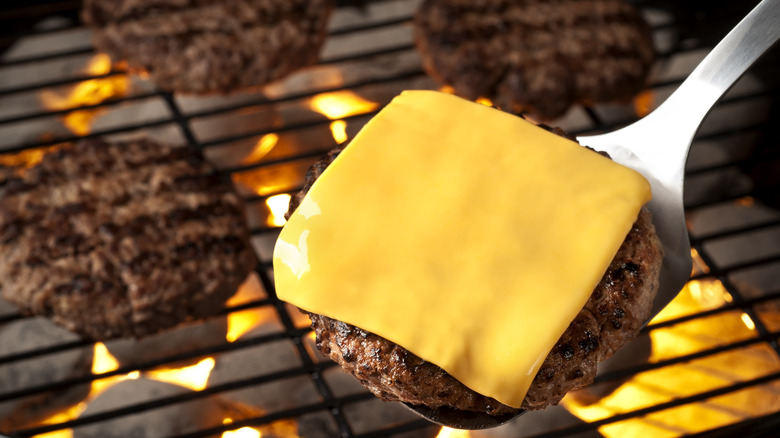 Burger on grill with American cheese