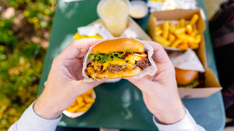 hands holding a cheeseburger