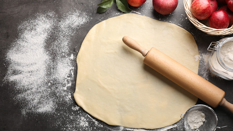 pie crust dough rolled out with rolling pin and apples