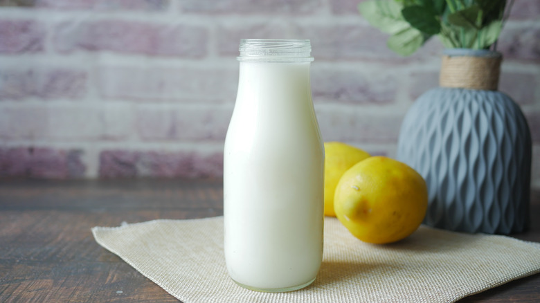 Bottle of milk with lemons on table