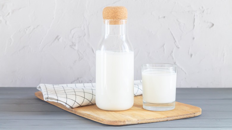 Bottle and glass of buttermilk on cutting board