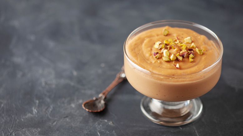 glass of butterscotch pudding with nuts