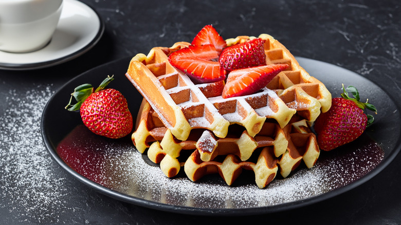 homemade cake batter waffles on a plate with a cappuccino on a dark background