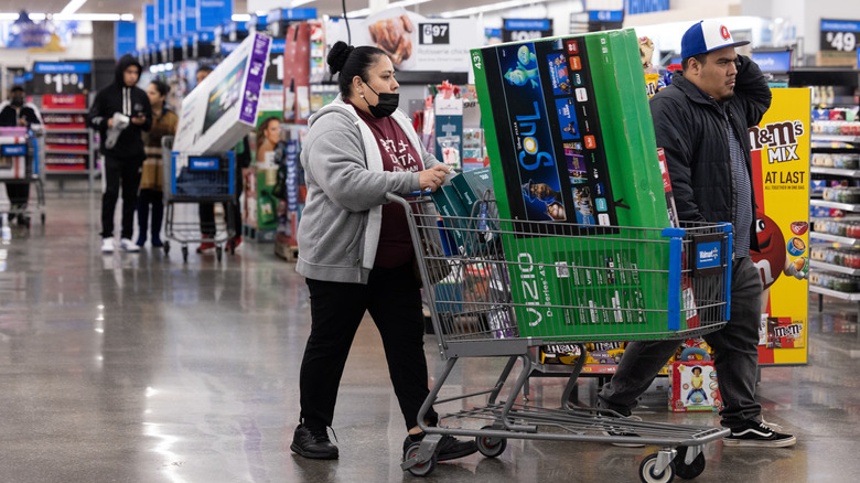 Shoppers with  television in a cart