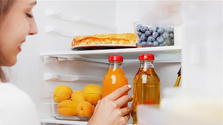 Person refrigerating juice bottles