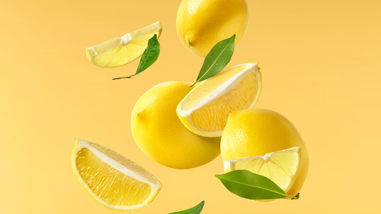 Whole and sliced lemons falling
