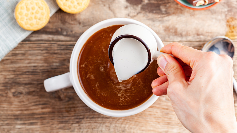 Pouring creamer into coffee