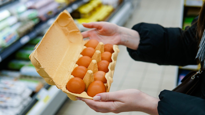 Customer holding open egg carton in supermarket