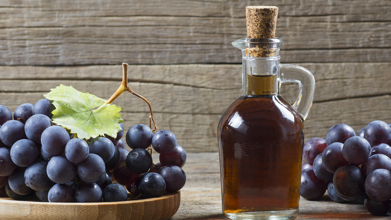 Glass bottle of vinegar with red grapes