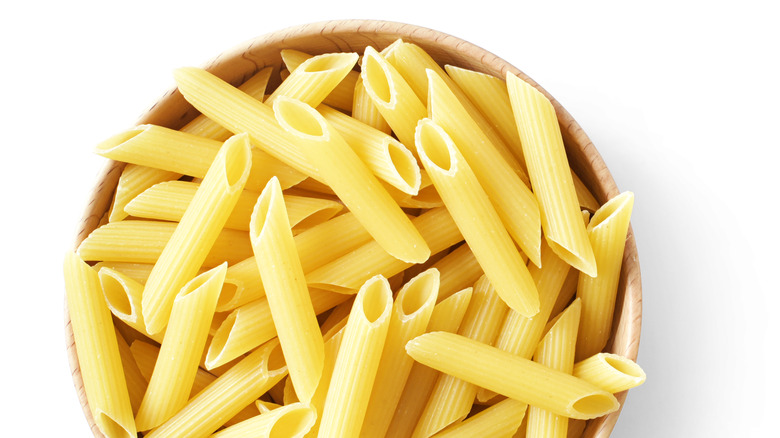 Dry penne noddles in a bowl.