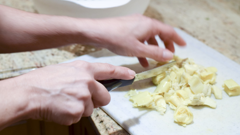 Person dicing canned artichokes