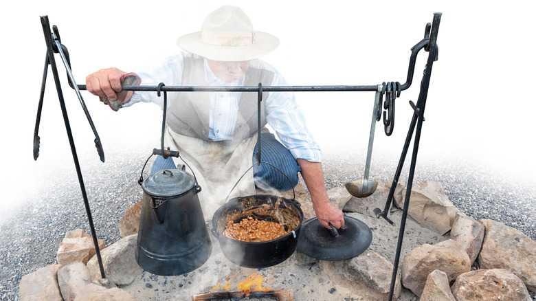 cowboy cooking beans over fire