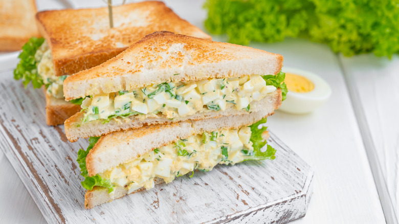 toasted egg salad sandwiches on wooden board