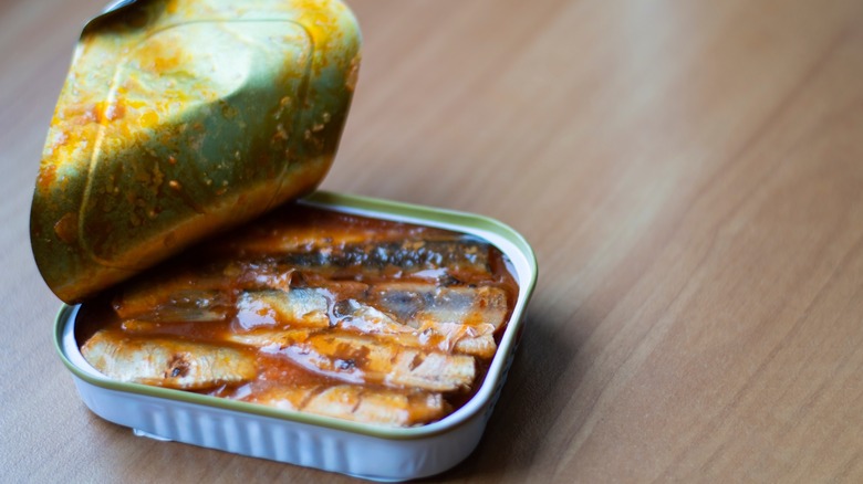 Canned sardines in a tin can on a wooden table