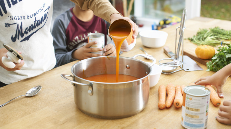 pouring tinned soup into pot