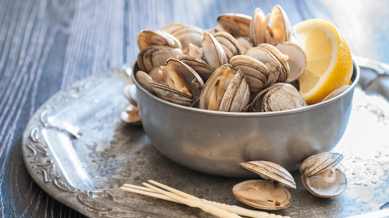 Metal bowl of fresh clams with a lemon wedge