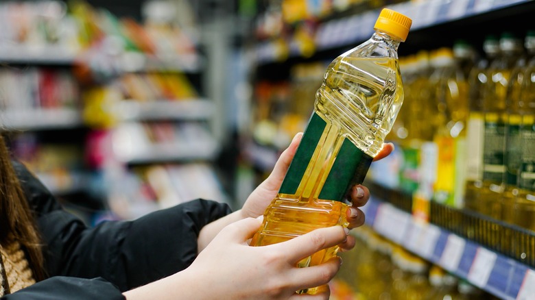 person holding bottle of cooking oil grocery store