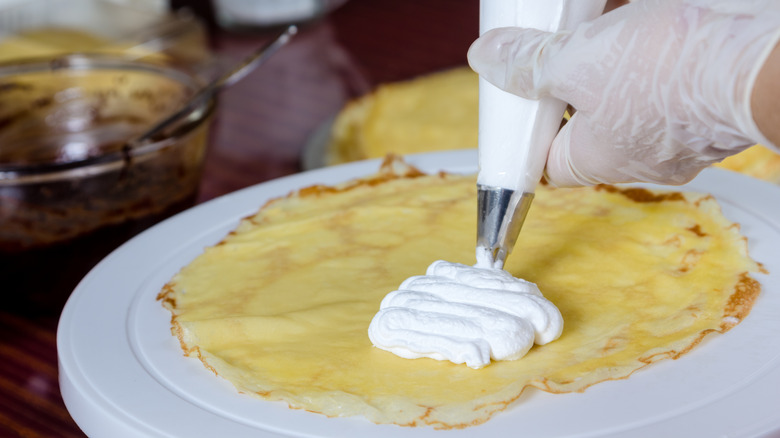 Piping frosting onto a crepe