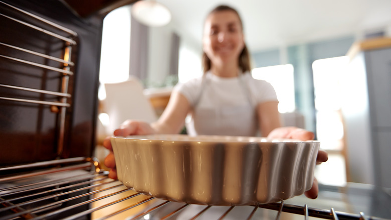 woman putting baking dish in oven