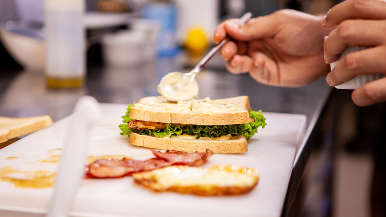 person making club sandwich