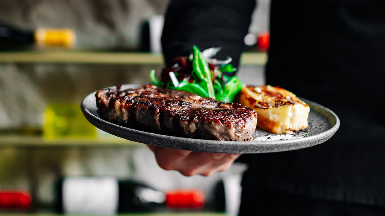 Restaurant server holding steak dish