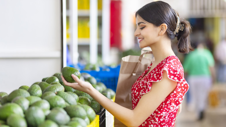 Woman choosing avocado at market