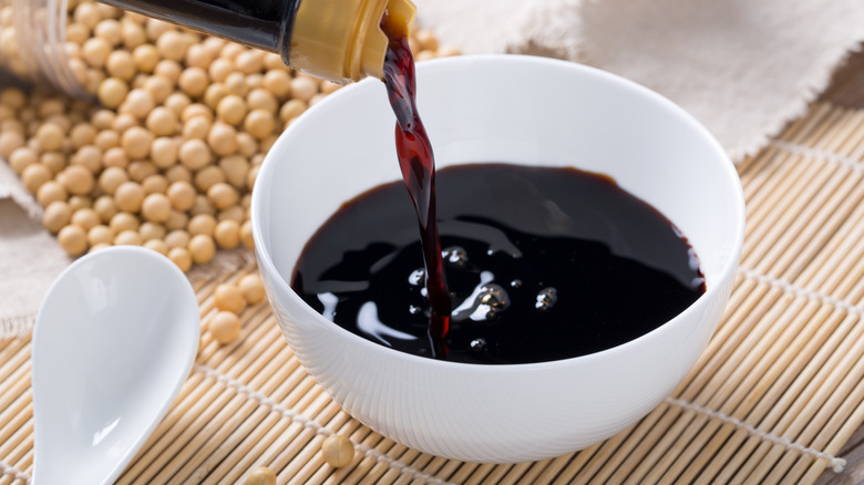 pouring soy sauce into white bowl