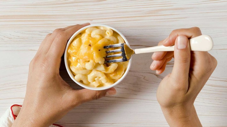 hand with fork scooping into mac and cheese
