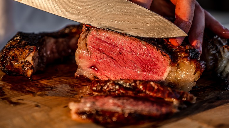 cutting steak to show the pink interior