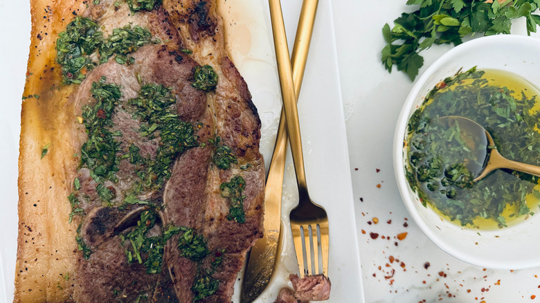 pork steak with chimichurri next to bowl of chimichurri