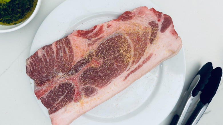 pork steak with salt and garlic powder on white plate