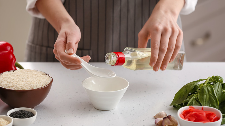 Hands pouring vinegar into ceramic dish