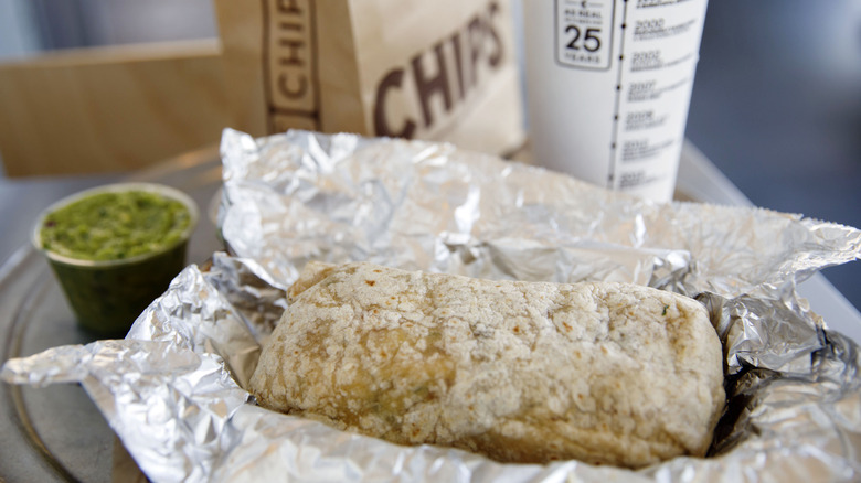 Chipotle burrito in foil with side of guacamole