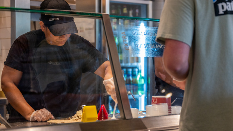 Chipotle worker assembling burrito