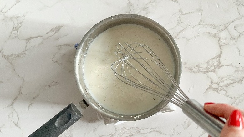 whisking up sauce in saucepan