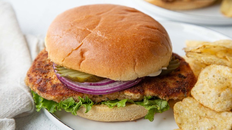 fried pork chop sandwich with potato chips