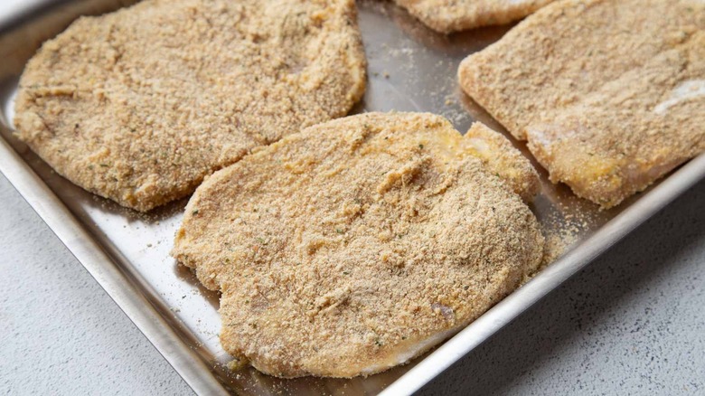 breaded pork chops on a sheet pan