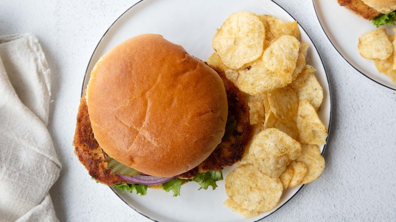 fried pork chop sandwich with potato chips