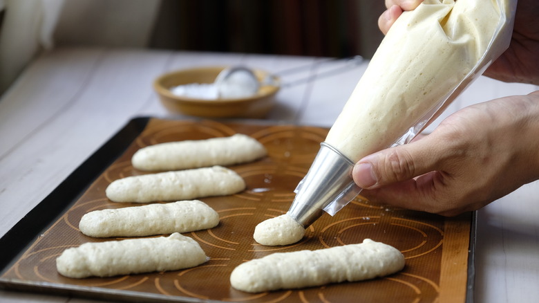 piping ladyfingers on cookie sheet