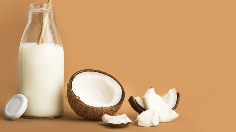 A coconut beside fresh coconut milk