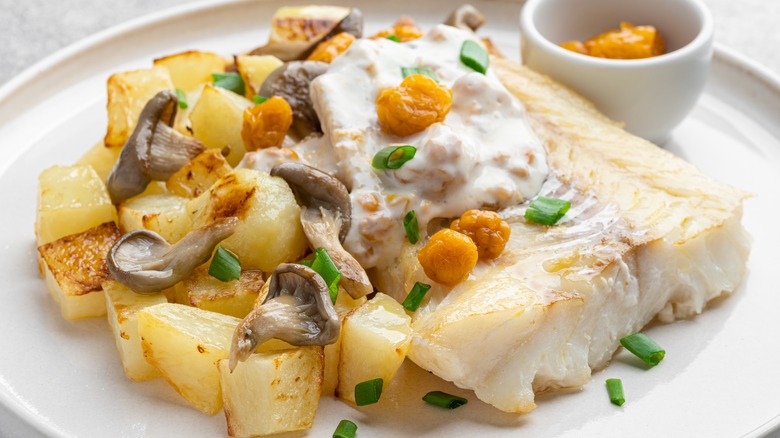 cod served on a plate with cloudberries and cloudberry jam