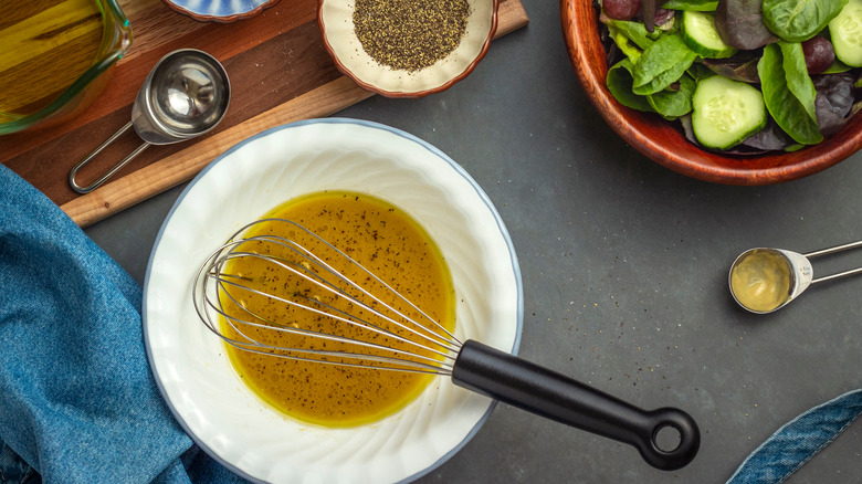 bowl of vinaigrette next to a salad